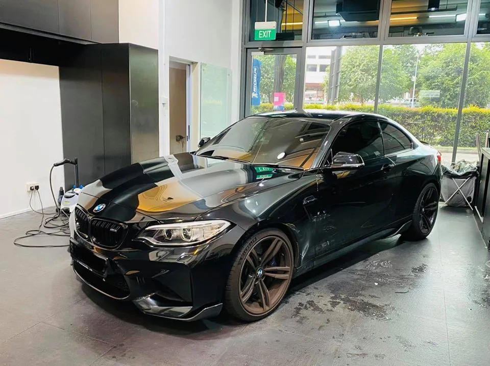 Black BMW M2 coupe with bronze wheels parked at Infratint Singapore after window tinting