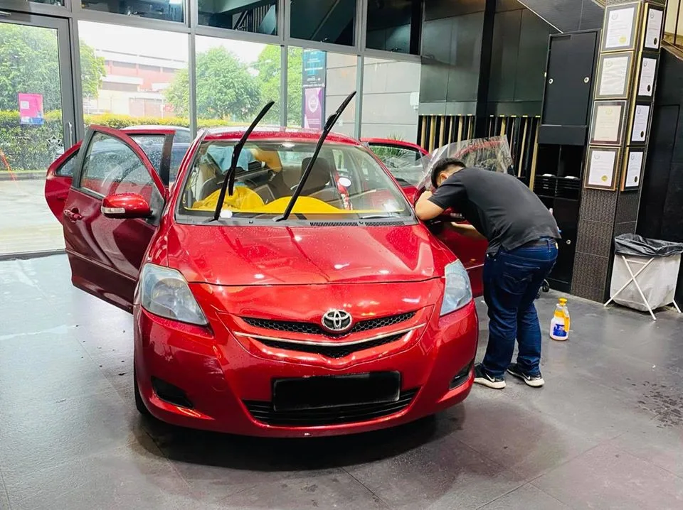 Red Toyota sedan having its windscreen prepped for window tinting at Infratint Singapore