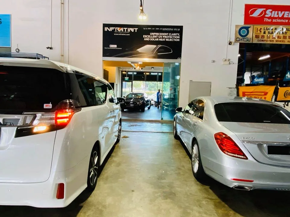 White MPV and silver Mercedes-Benz sedan parked outside the Infratint Singapore entrance