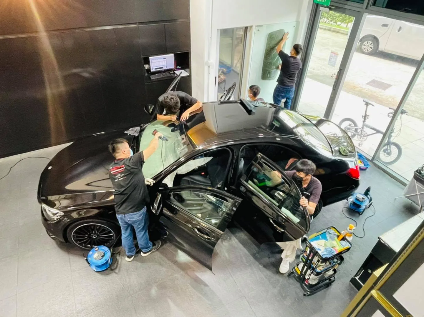 Team tinting a black sedan seen from above at Infratint Singapore