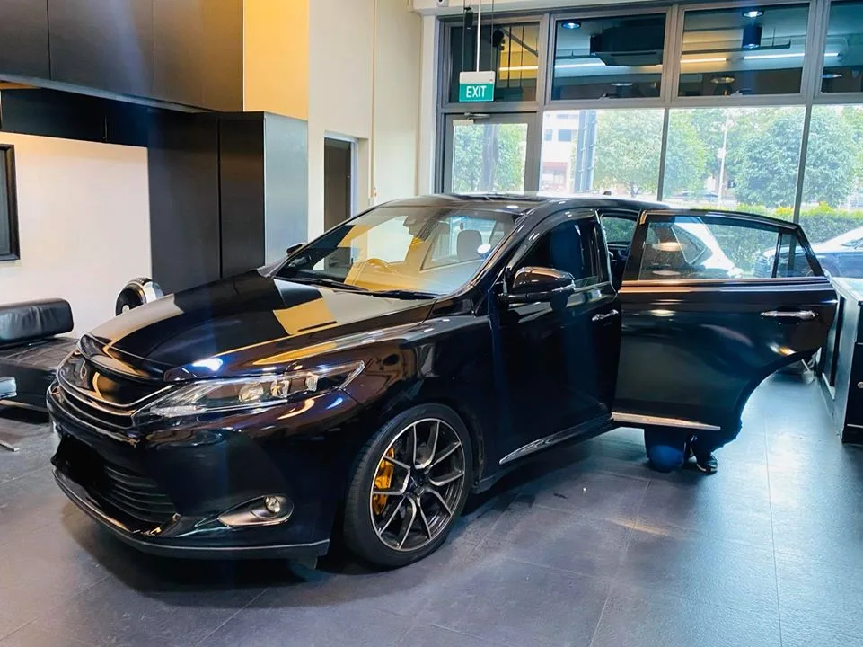 Black Toyota Harrier side profile with a technician fitting film at Infratint Singapore