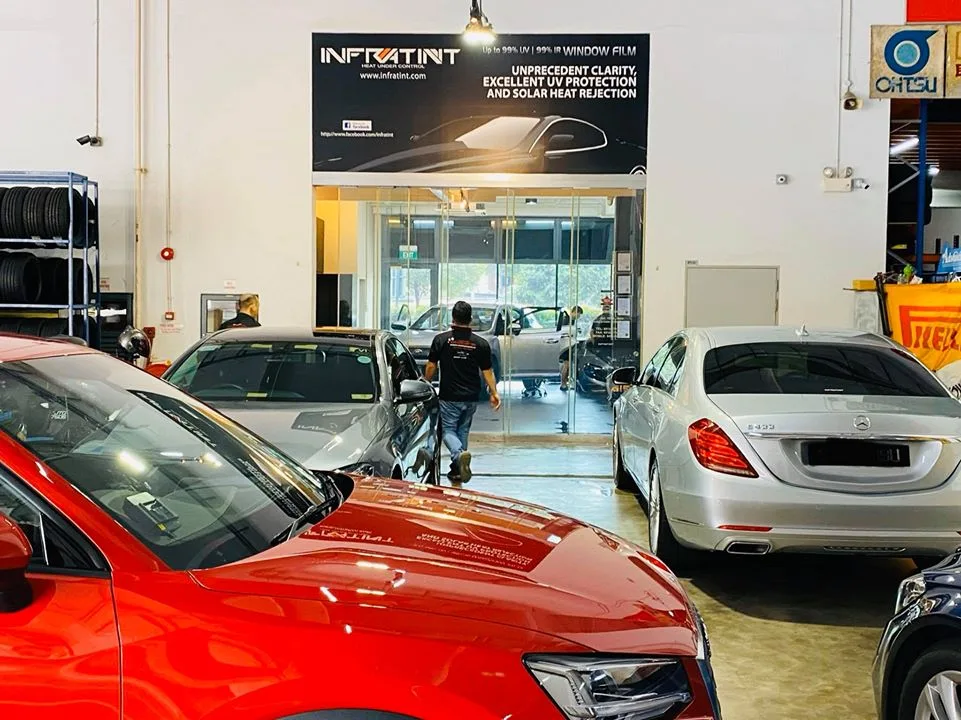 Red Audi SUV and silver Mercedes-Benz S-Class inside the busy Infratint Singapore install bay
