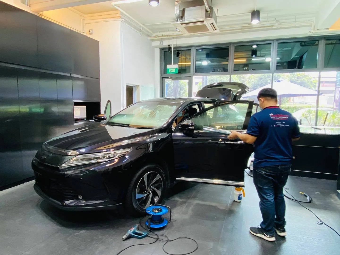 Installer applying window film to a black Toyota Harrier at Infratint Singapore