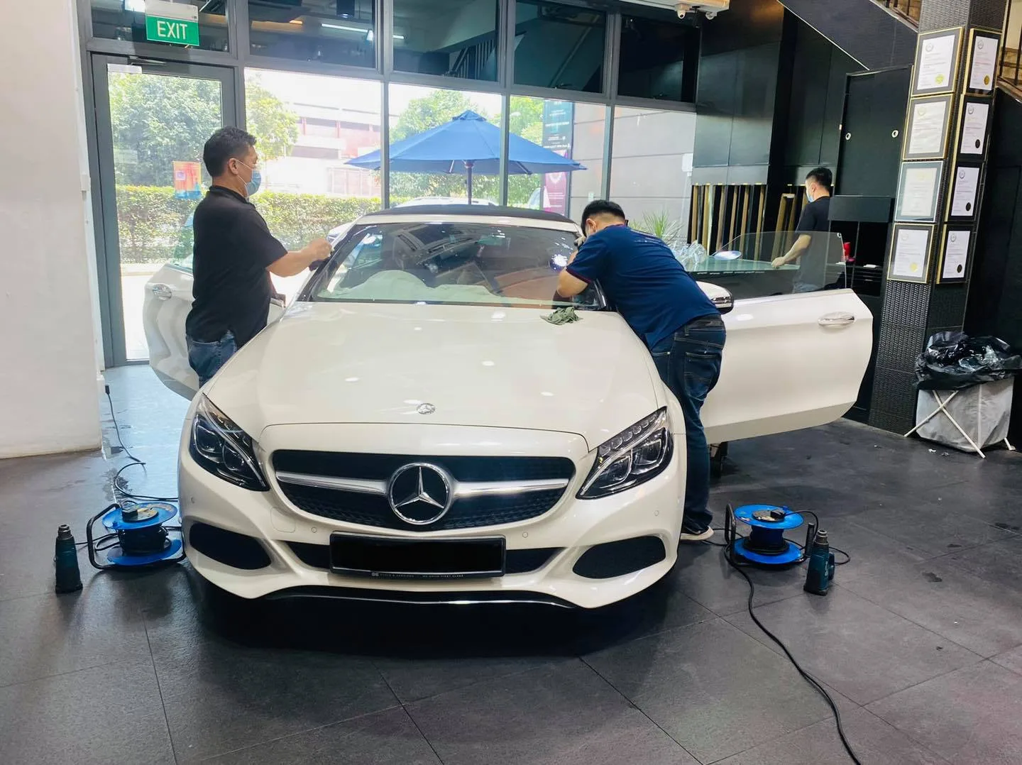 Two installers tinting a white Mercedes-Benz convertible at Infratint Singapore