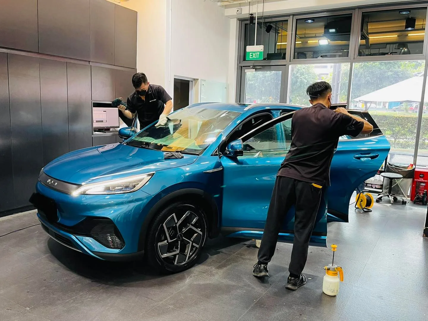 Blue BYD Atto 3 front three-quarter during window film install at Infratint Singapore
