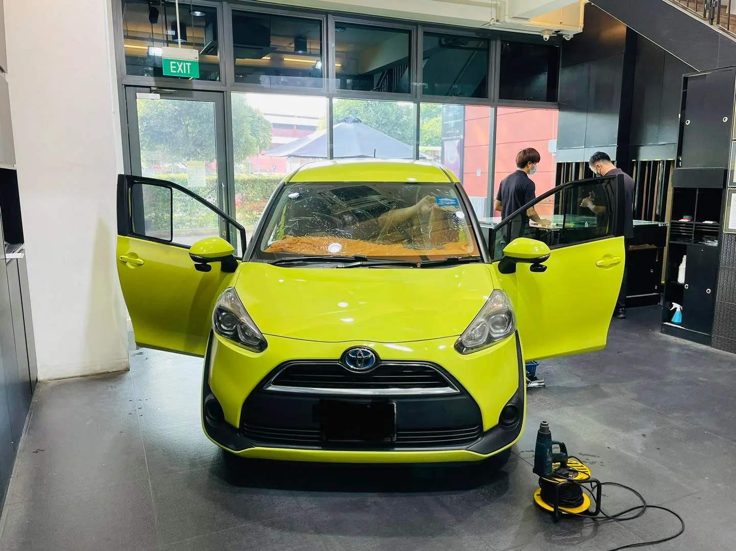 Lime green Toyota Sienta with doors open during window tinting at Infratint Singapore