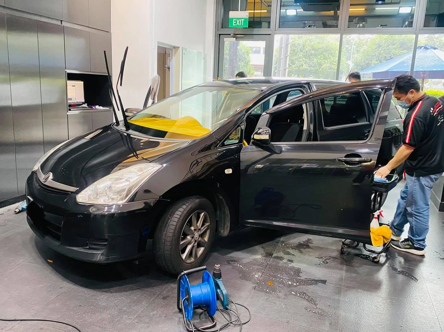 Installer tinting the rear door of a black Toyota Wish at Infratint Singapore