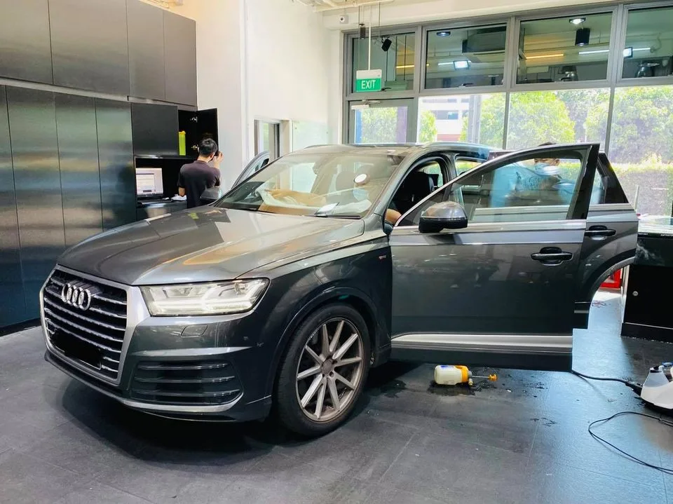 Installer tinting a grey Audi Q7 from the front three-quarter at Infratint Singapore