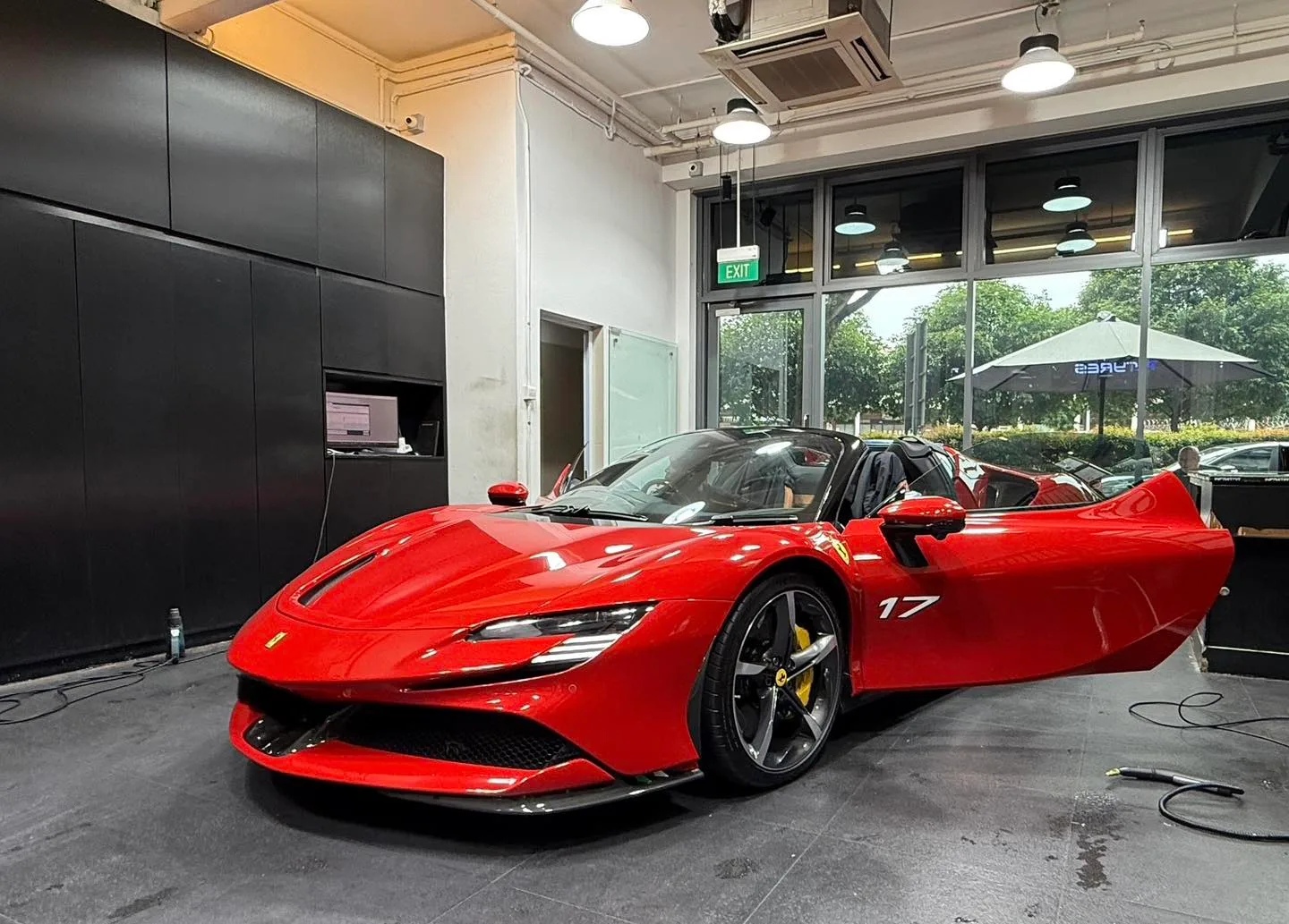 Red Ferrari SF90 with roof and door open inside the Infratint workshop