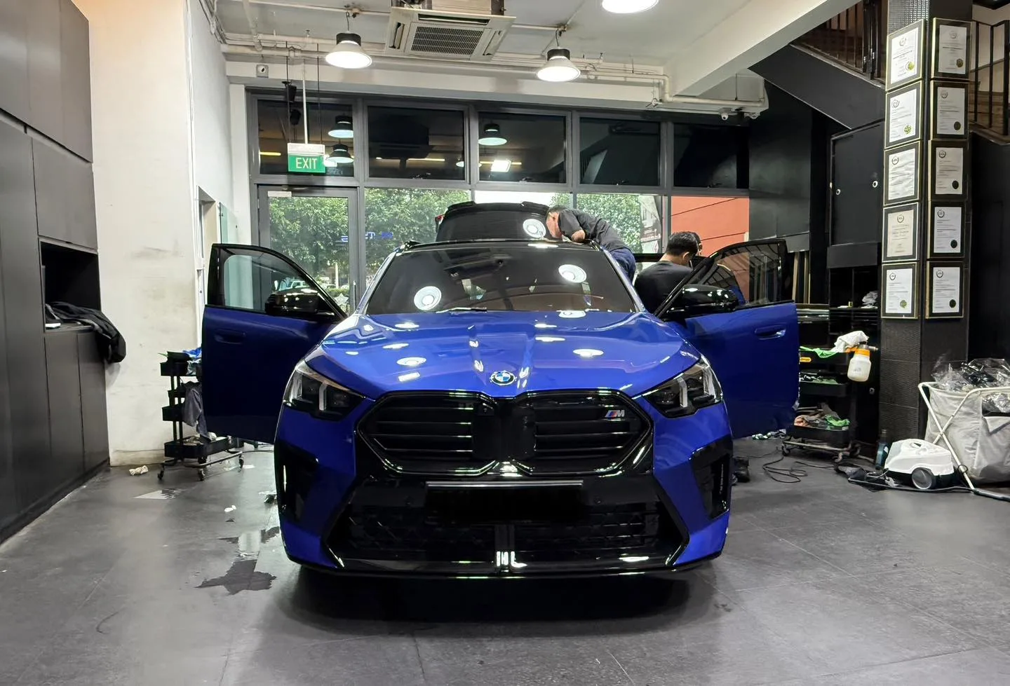 Blue BMW X2 front view inside Infratint workshop during film installation