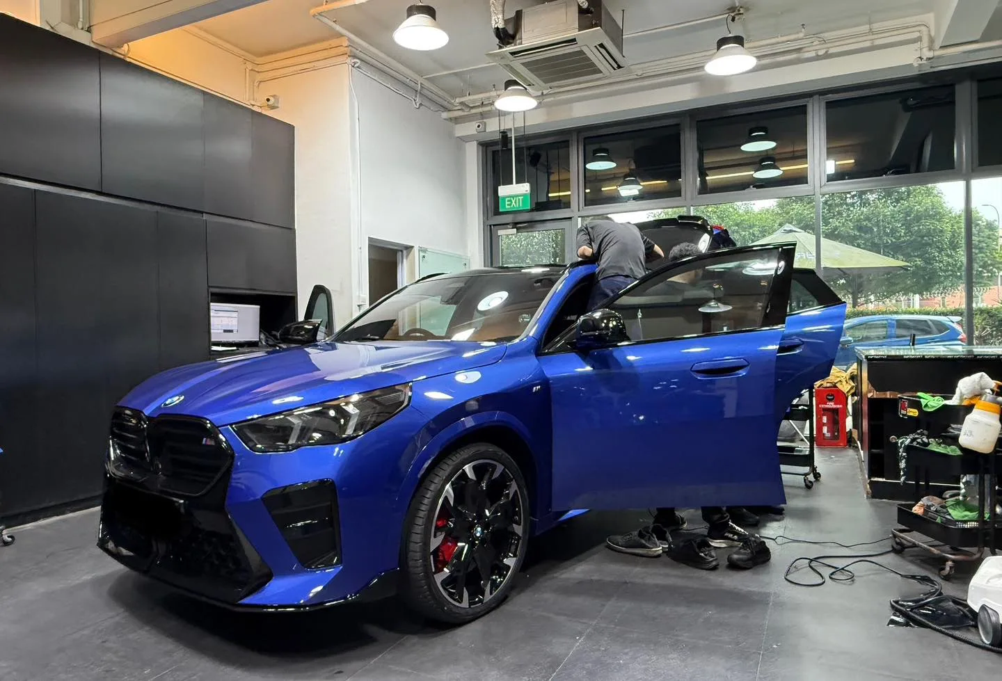 Blue BMW X2 with doors open during window film fitting at Infratint workshop