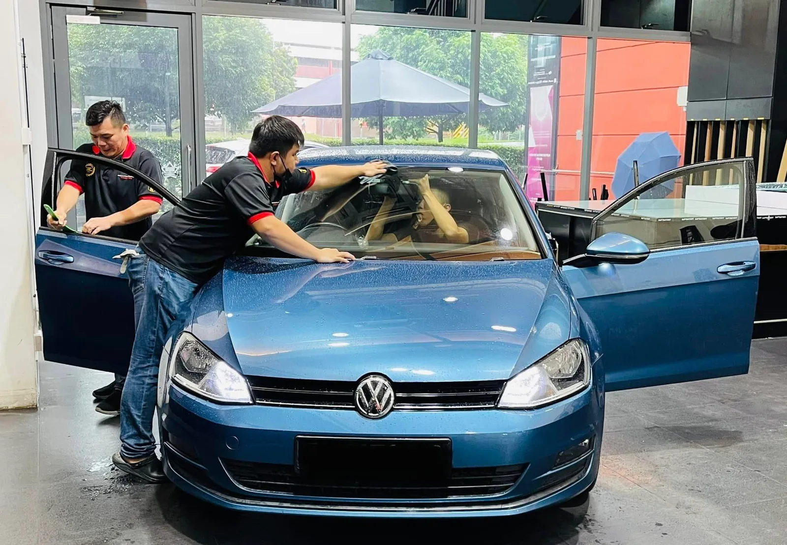 Blue Volkswagen Golf with two installers during window tinting at Infratint Singapore
