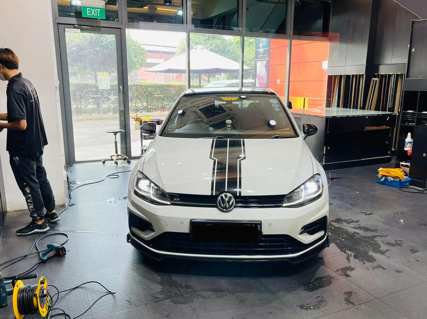 White Volkswagen Golf with racing stripes during window tinting at Infratint Singapore