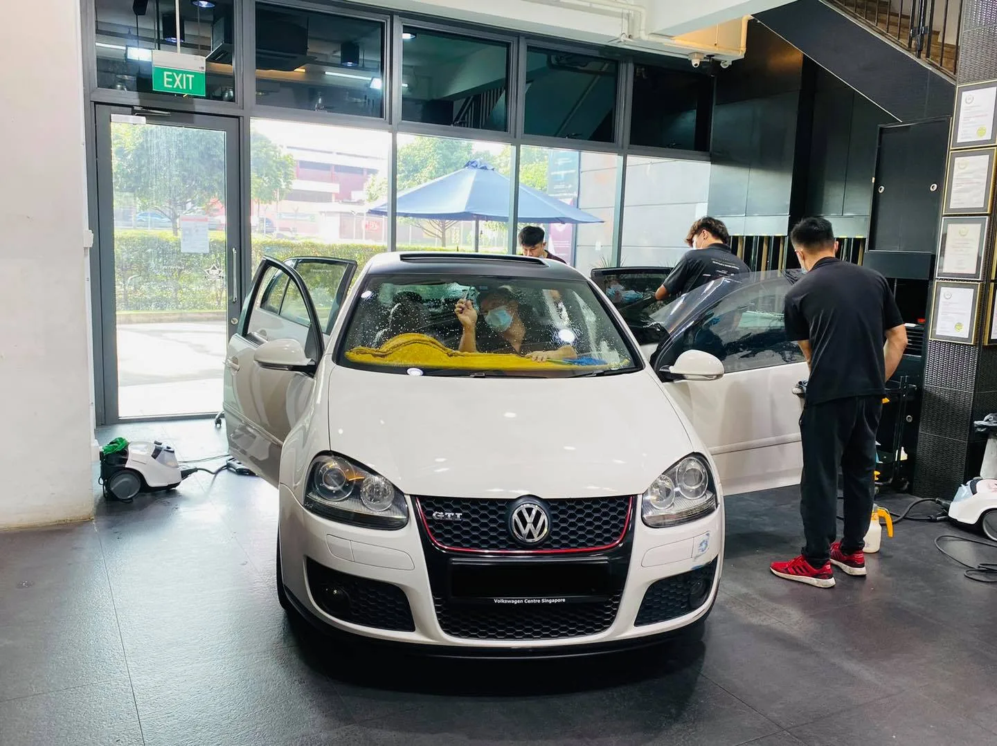 White Volkswagen Golf GTI with doors open during window tinting at Infratint Singapore