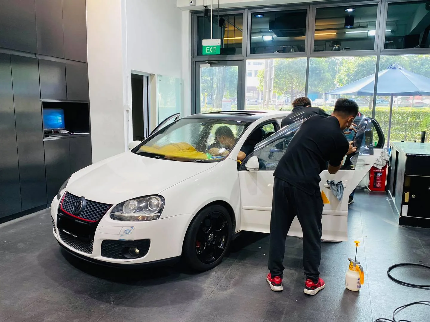 Installer applying window film to a white Volkswagen Golf GTI at Infratint Singapore