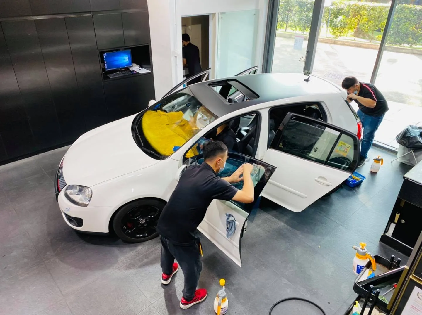 Overhead view of two technicians tinting a white Volkswagen Golf GTI at Infratint Singapore