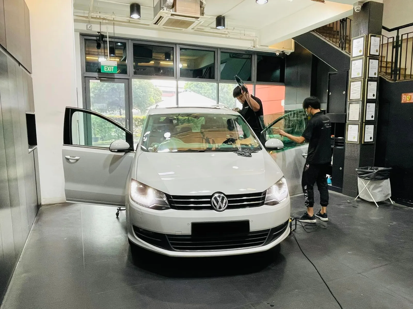 Tinters applying film to a white Volkswagen Sharan windscreen at Infratint Singapore