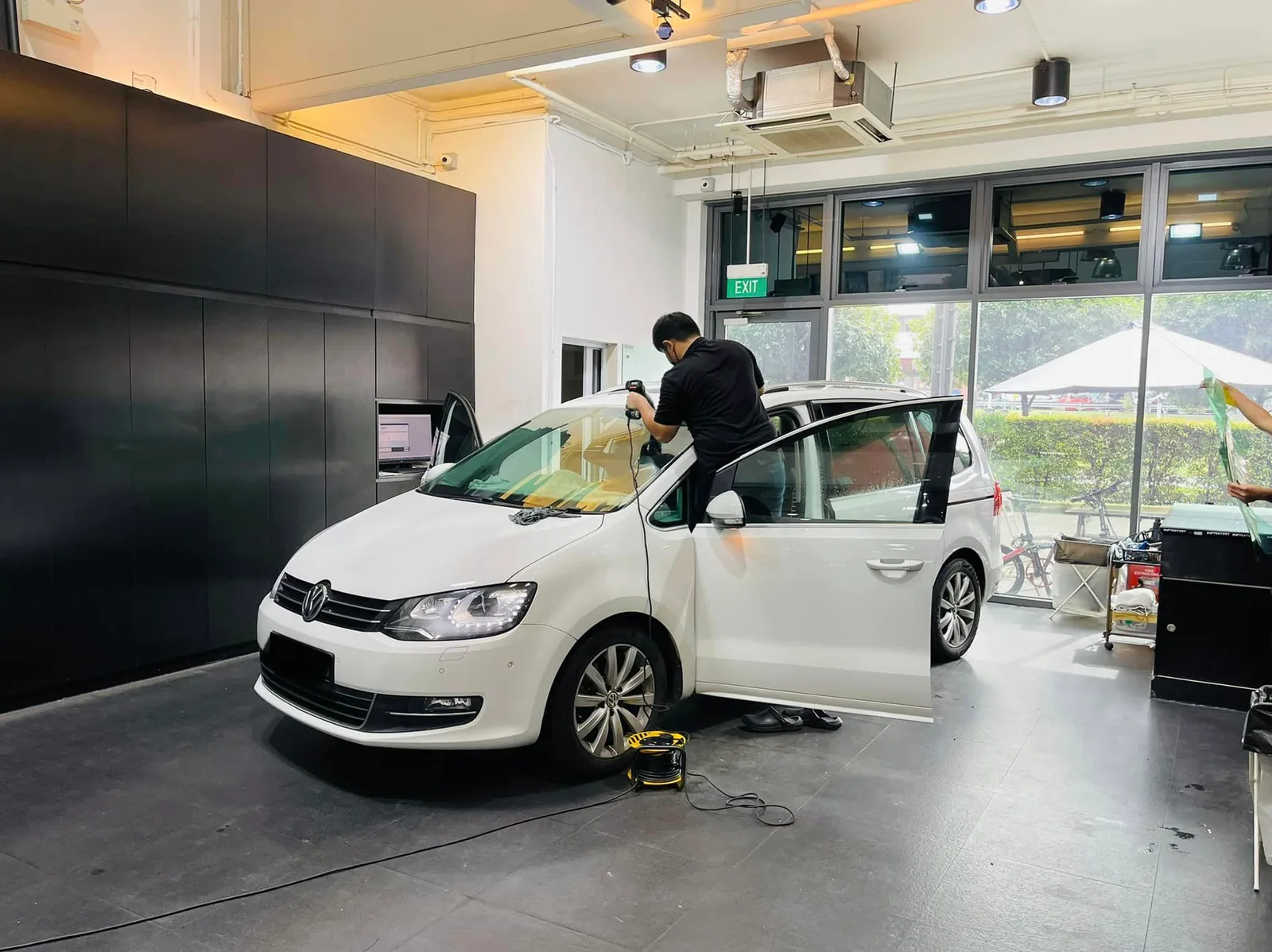 Tinter applying window film to the door of a white Volkswagen Sharan at Infratint Singapore