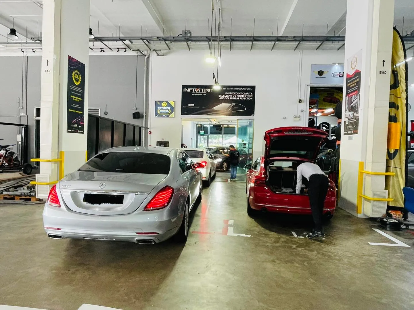 Silver Mercedes-Benz sedan and a red car in the Infratint Singapore install bay