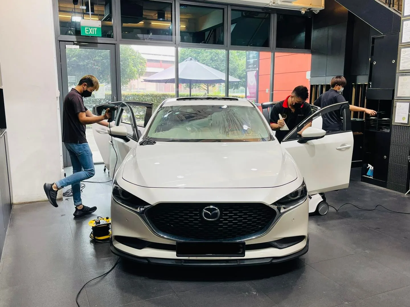 White Mazda crossover being tinted by three installers at Infratint Singapore