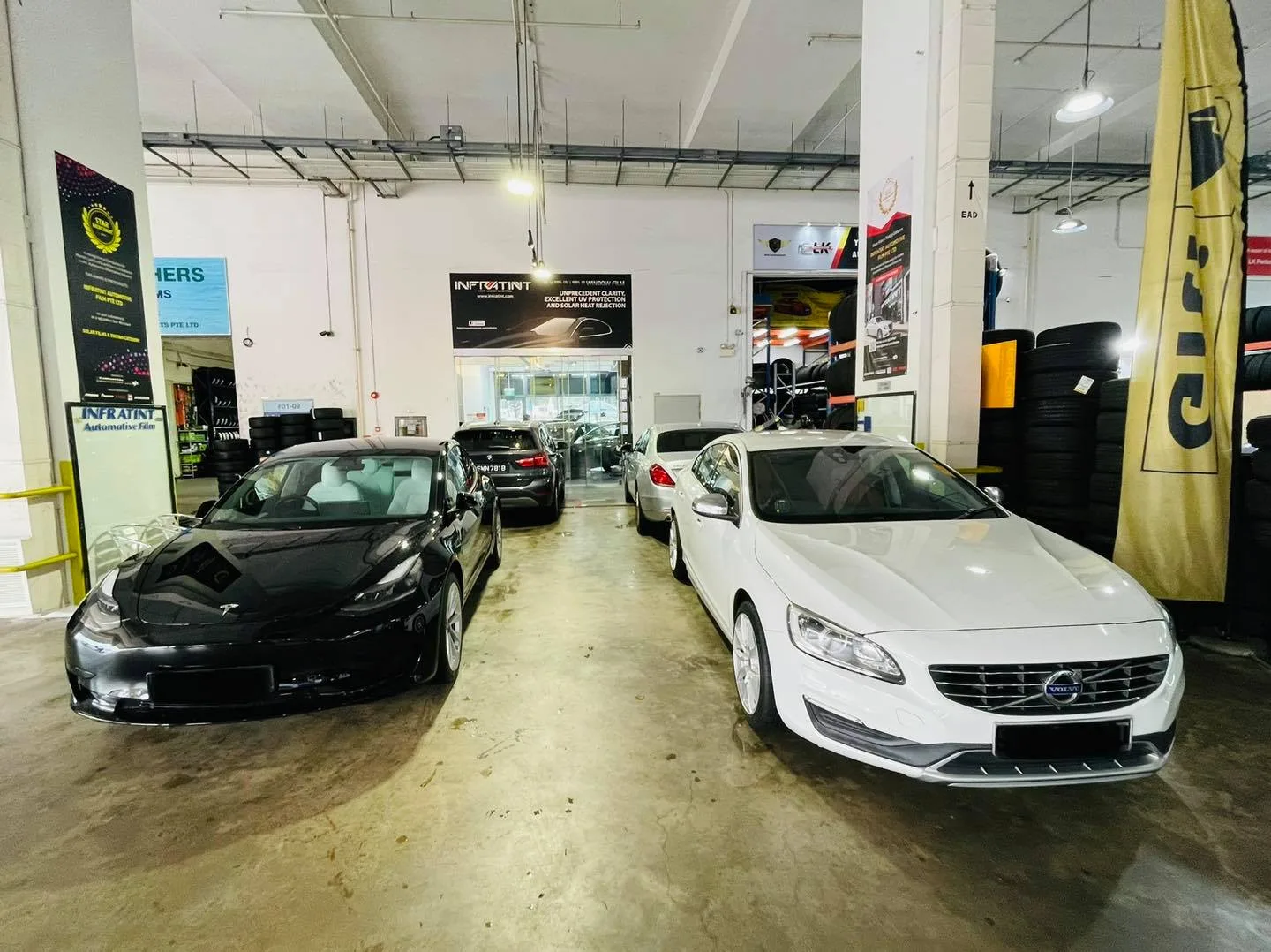 White Volvo S60 beside a black Tesla Model 3 at Infratint Singapore