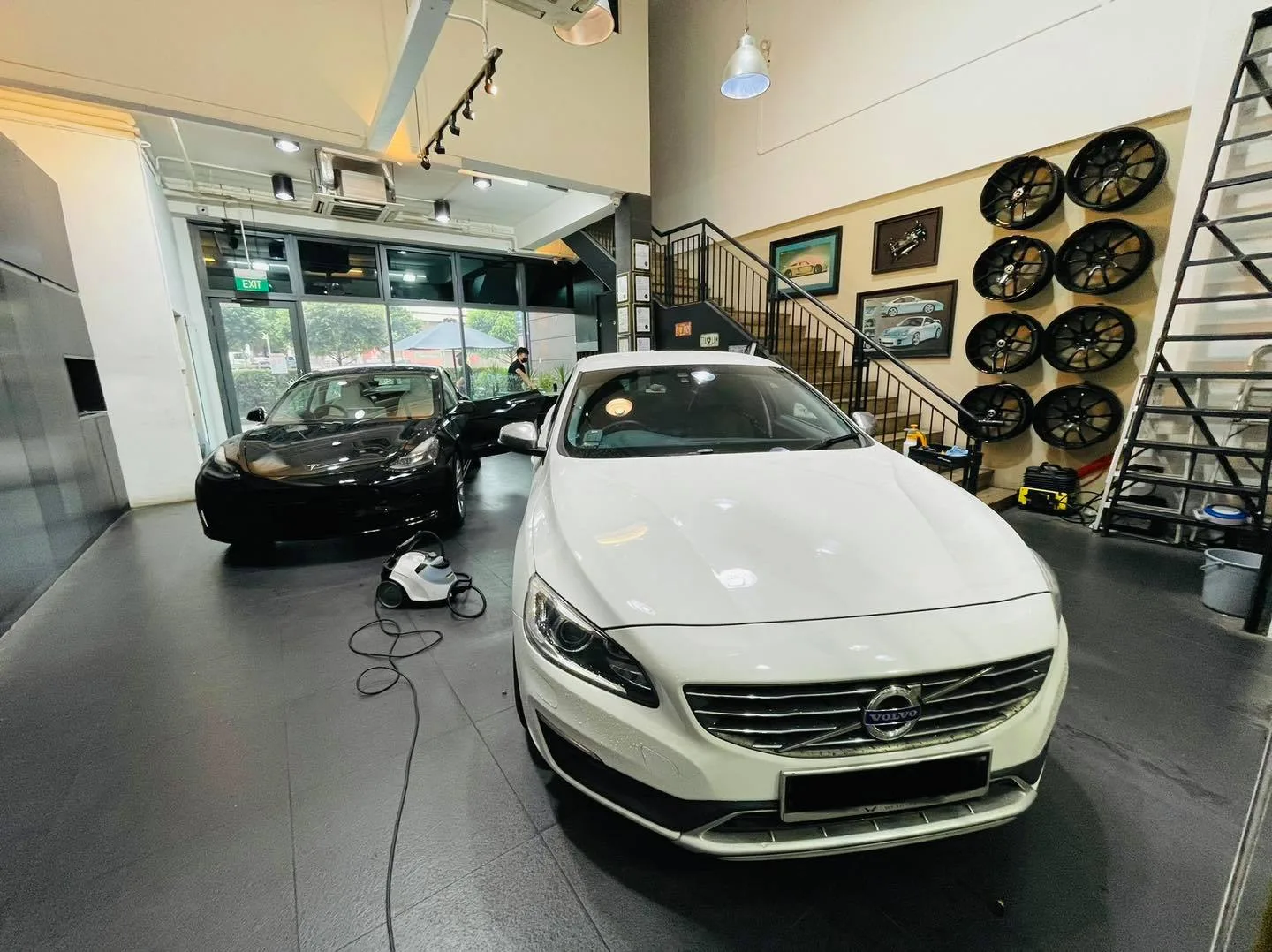 White Volvo S60 and black Tesla in the showroom at Infratint Singapore