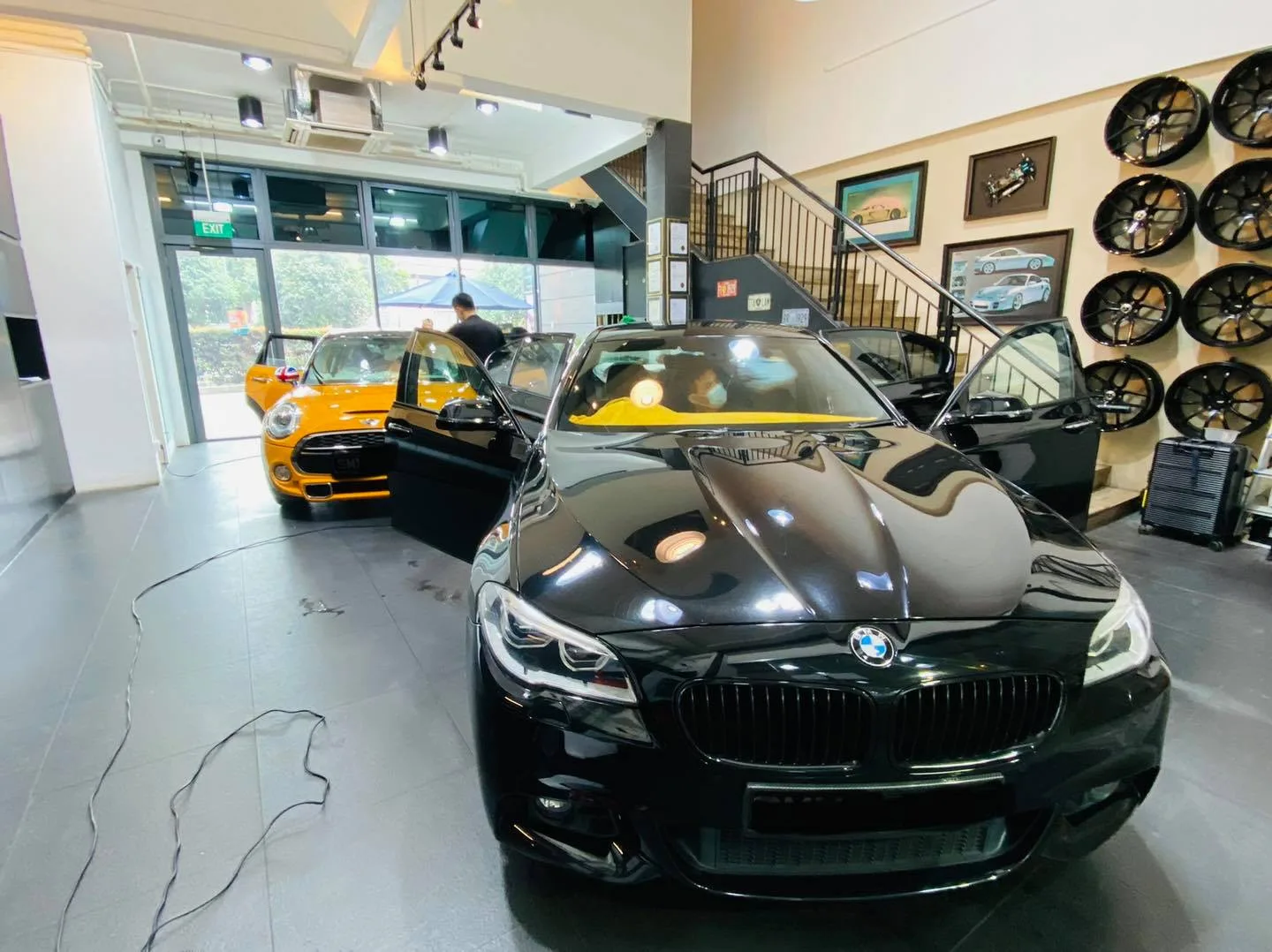 Black BMW 5 Series and orange Mini Cooper inside the Infratint Singapore workshop