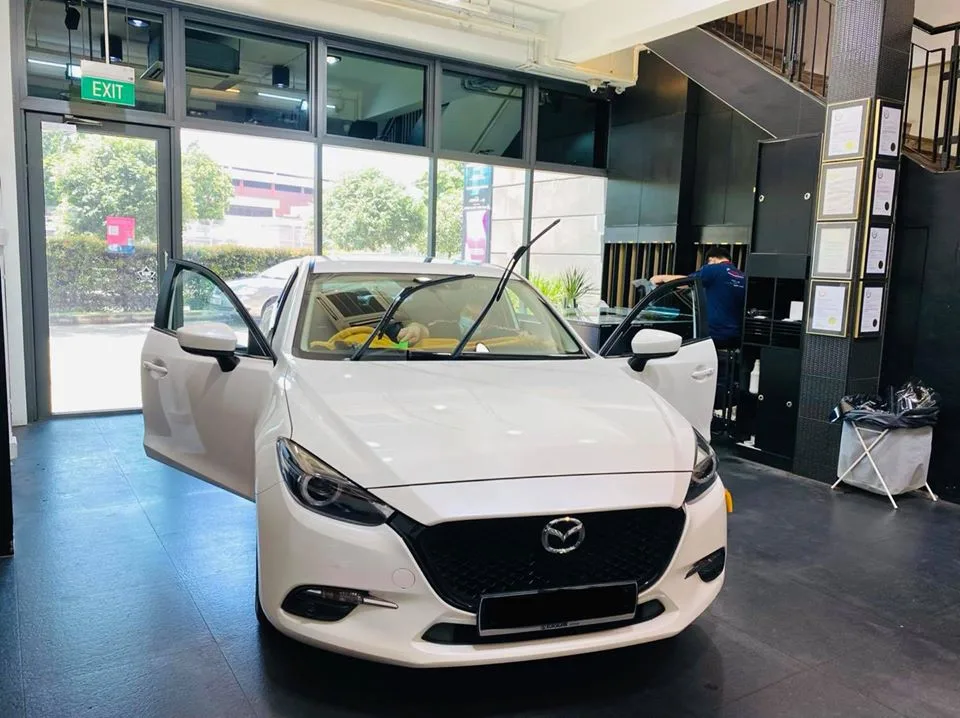 White Mazda 3 sedan with driver door open during window tinting at Infratint Singapore