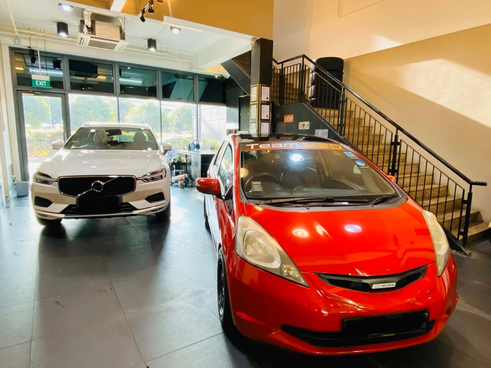 Red Honda Fit and white Volvo XC60 inside Infratint Singapore for window tinting