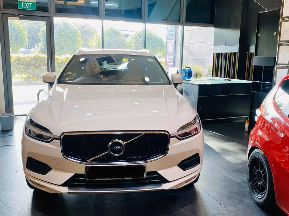 White Volvo XC60 SUV front view beside a red Honda Fit at Infratint Singapore