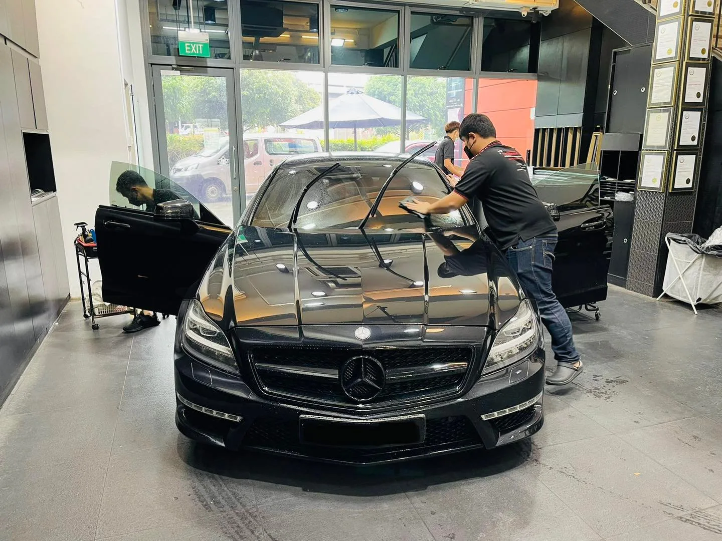 Technician tinting the windscreen of a black Mercedes-Benz CLS at Infratint Singapore