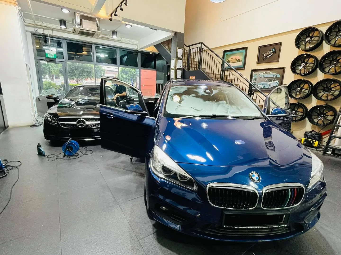 Blue BMW and a black Mercedes-Benz sedan inside the Infratint Singapore showroom
