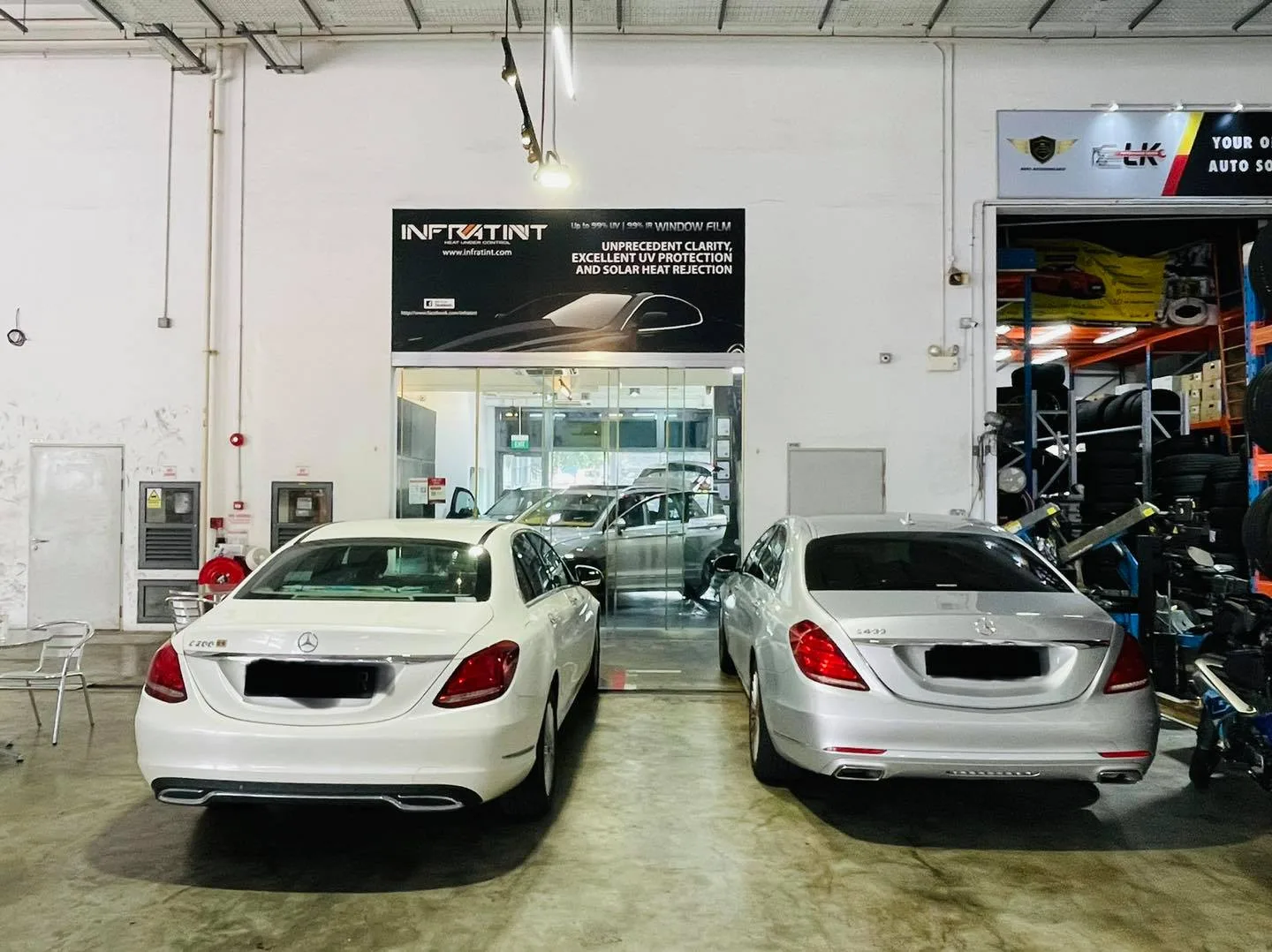 Two white Mercedes-Benz sedans parked under the Infratint banner in Singapore