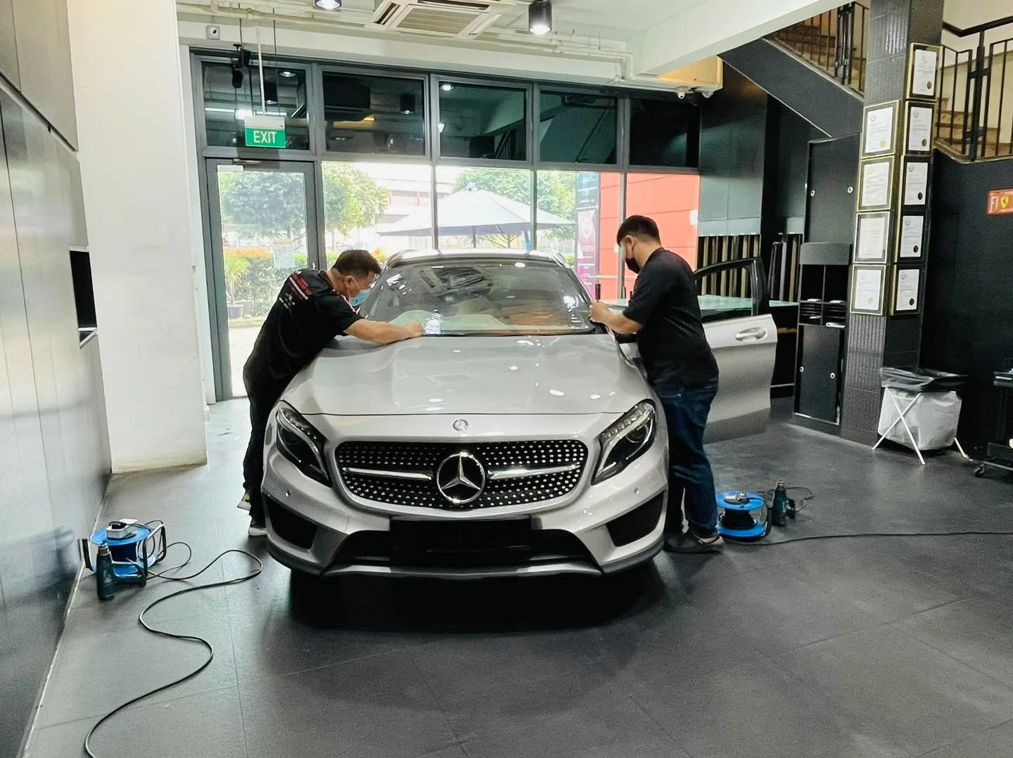 Silver Mercedes-Benz GLA SUV being tinted at the windscreen by two technicians at Infratint Singapore
