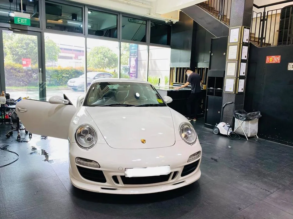 White Porsche 911 with door open inside the Infratint Singapore showroom for window tinting
