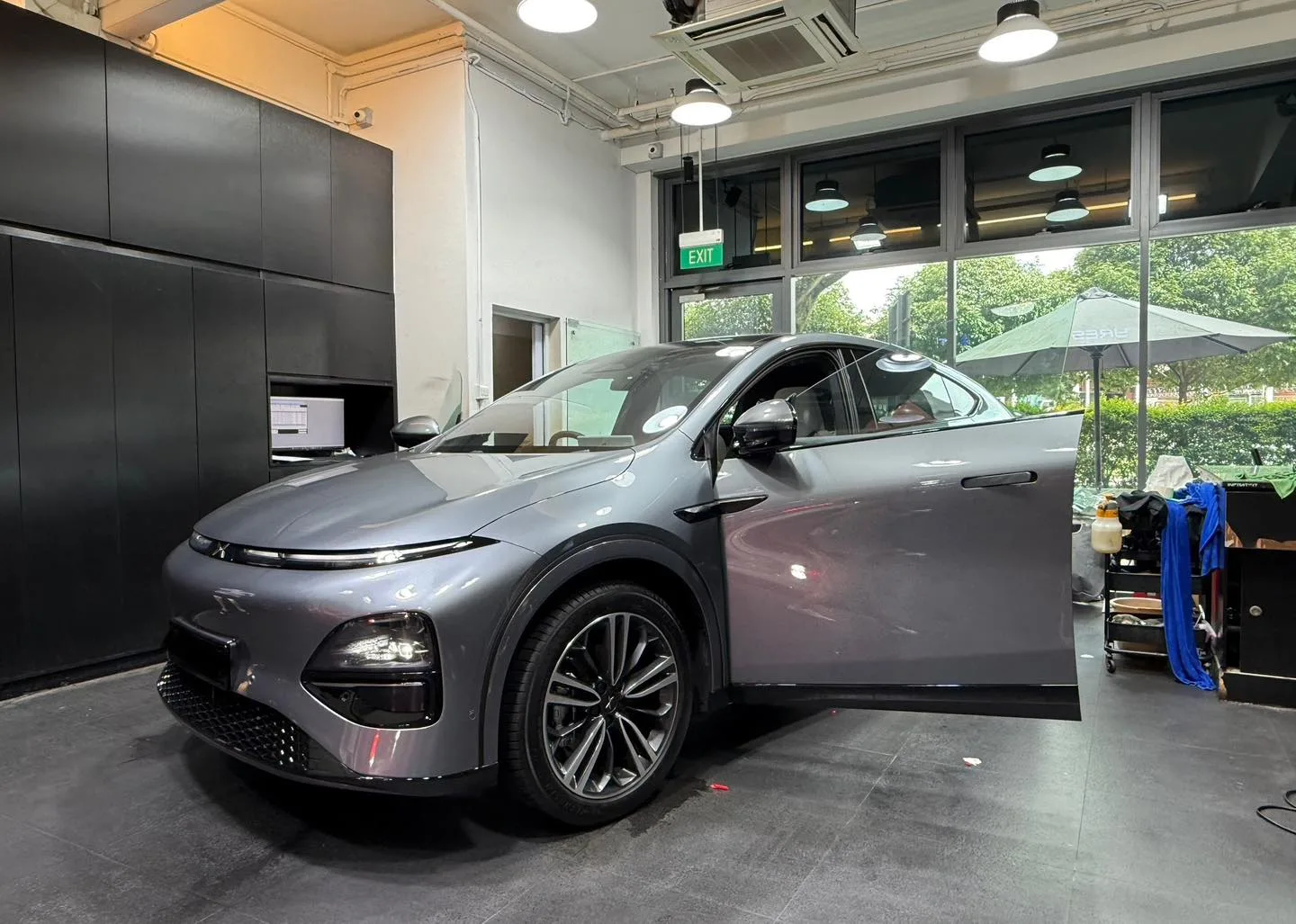 Grey XPENG G6 with driver door open during window film installation at Infratint workshop