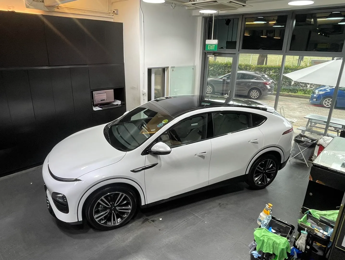 Overhead view of white XPENG G6 panoramic glass roof inside Infratint workshop