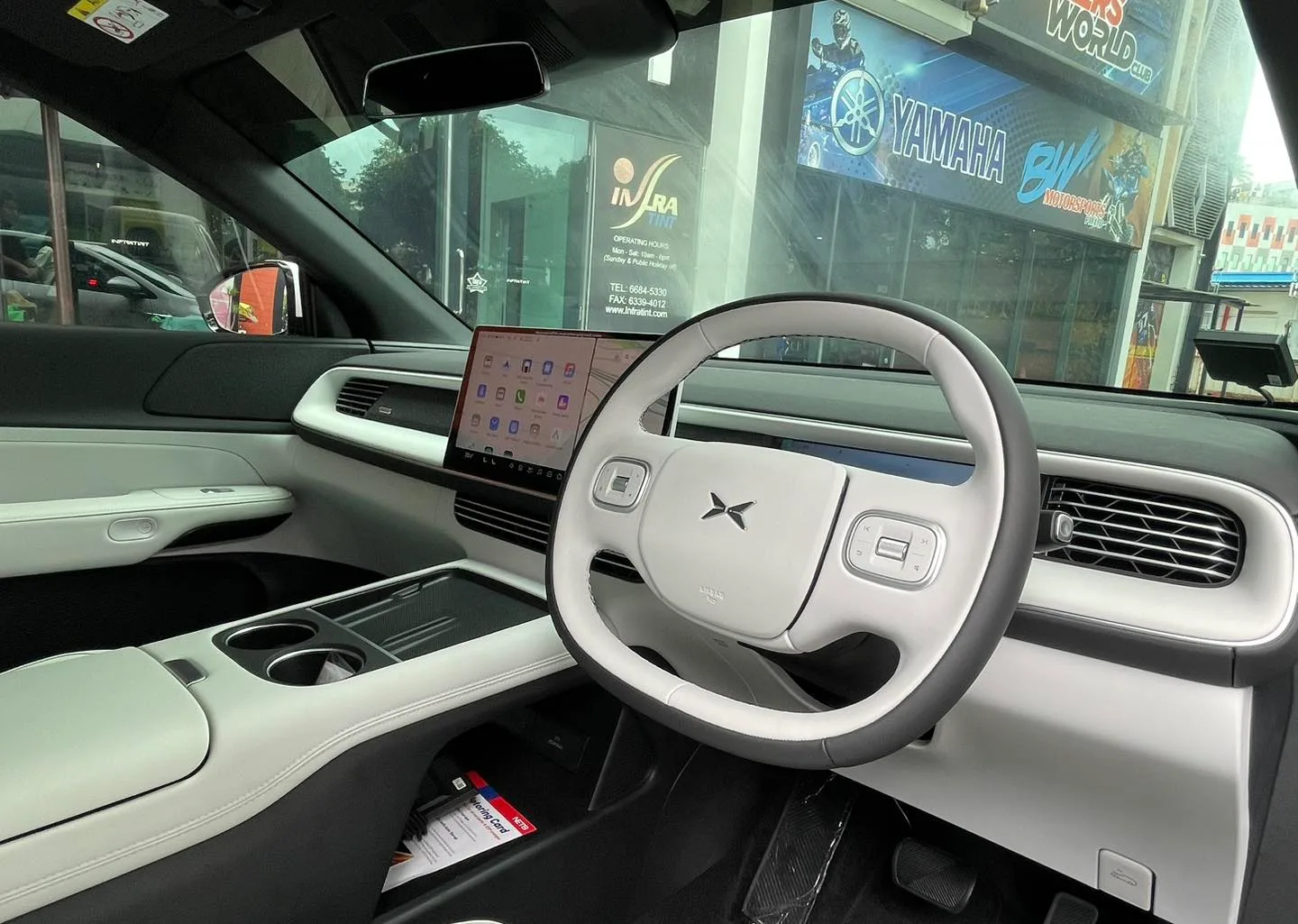 XPENG G6 light grey interior with central touchscreen seen through tinted glass at Infratint Singapore